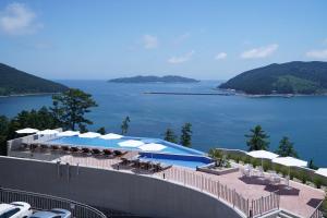 巨济Hotel SANG SANG & Private SANG SANG POOL VILLA的一个带遮阳伞的游泳池,享有水景