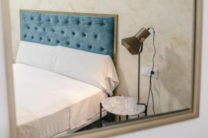赫雷斯-德拉弗龙特拉Villamarta Boutique Rooms的镜子反射着一间卧室,卧室配有一张床和一张桌子