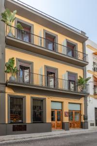 赫雷斯-德拉弗龙特拉Villamarta Boutique Rooms的黄色的建筑,设有窗户和阳台