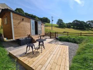 霍普Peak District Shepherds Hut的小屋前的木甲板上配有桌椅