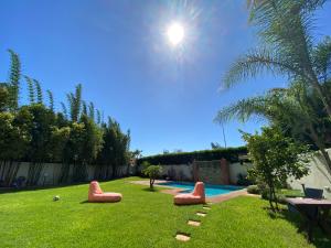 卡萨布兰卡Lilas Park Villa - Casablanca Bouskoura的后院,带红色椅子的游泳池,在草地上