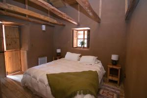AlcoguazHotel Casona Distante的一间带一张大床的卧室,位于一个拥有木制天花板的房间