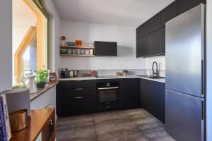 索波特Loved Up Sea Home的厨房配有黑色橱柜和不锈钢冰箱