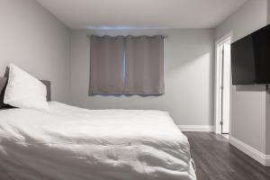 滑铁卢PRIVATE ROOM ENSUITE UPTOWN WATERLOO - e5的卧室配有白色的床和电视。
