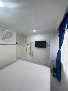 麦德林Casa Hotel Manco Mora的卧室配有白色的床和电视