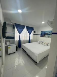 麦德林Casa Hotel Manco Mora的一间卧室配有一张带蓝色窗帘的大床