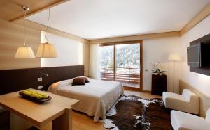 圣维托-迪卡多雷拉帝妮亚公园酒店的一间卧室配有一张床、一张桌子和一个窗户。