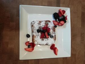 StanddaarbuitenBed and Breakfast Bianca的一块蛋糕,上面有水果,放在一个白盘上