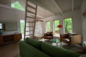 伦讷Oak Cottage near Rønne & Beach的客厅设有绿色沙发和梯子