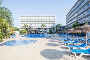 萨洛黄金海岸索尔酒店的一个带椅子和遮阳伞的游泳池以及酒店