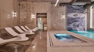克拉科夫Hotel H15 Luxury Palace的一个带椅子的游泳池和一个游泳池的房间