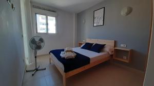 马略卡岛帕尔马Toros Apartamentos的一间卧室配有一张带蓝色枕头的床和风扇