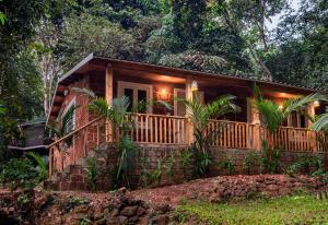CurtorimNirvana Hill Resort的树林中的小屋,设有门廊和甲板