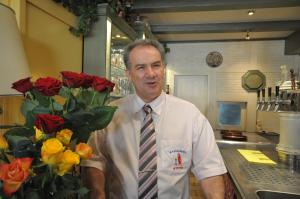 Münstermaifeld"雅典"餐厅酒店的一个人在厨房里,有一束玫瑰花