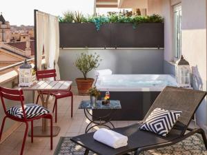 罗马罗马科索里亚斯特美居酒店的阳台的热水浴池,配有桌椅