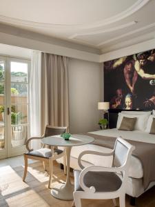 罗马Villa Agrippina Gran Meliá – The Leading Hotels of the World的一间卧室配有一张大床和一张桌子及椅子