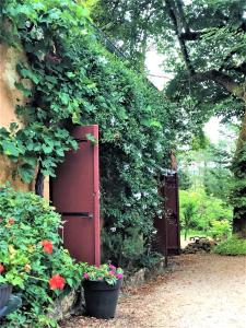 Saint-AlvèreChambres d'hotes Les Coustilles的花园,有红色的门和一些花