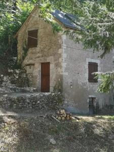 圣热尔韦拉福雷chez Pauline & Sébastien le Bien-être proche de la forêt的一座古老的石屋,有一扇门和一堆木头