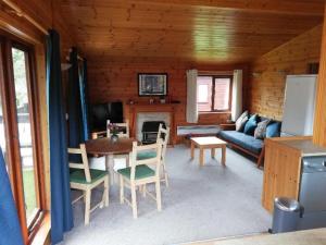 米尔福德昂西Wooden Forest Lodge by the sea的客厅配有桌椅和沙发