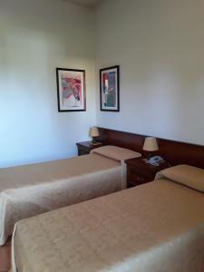 Azzano Decimo阿尔普提科酒店的酒店客房,设有两张床和两张墙上的照片