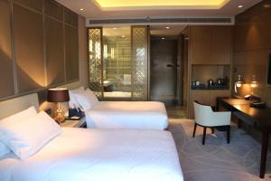 沈阳沈阳绿地铂瑞酒店的酒店客房设有两张床、一张书桌和一个厨房。