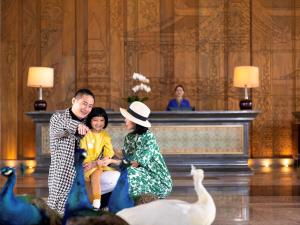 景洪市西双版纳融创铂尔曼度假酒店的坐在鹅旁边的男人、女人和孩子