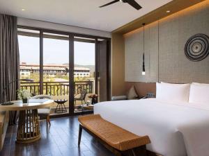 景洪市西双版纳融创铂尔曼度假酒店的酒店客房设有一张大床和一个阳台。