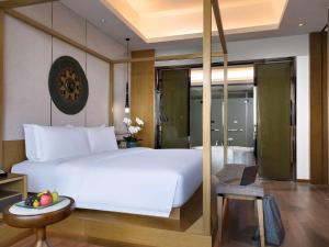 景洪市西双版纳融创铂尔曼度假酒店的卧室配有一张白色的大床和一张桌子