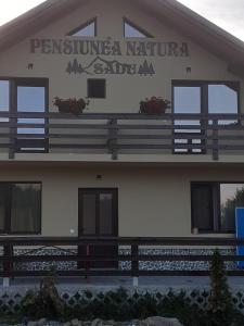 锡比乌Pensiunea Natura Sadu的建筑的侧面有标志