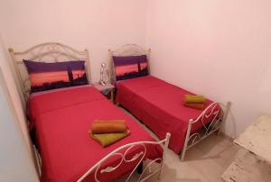 梅伦杜尼奥La Nuova Casetta的小客房内的两张床,配有红色床单