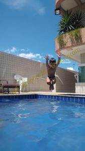 大普拉亚Apê Temporada Praia Grande/SP的跳过游泳池的男人