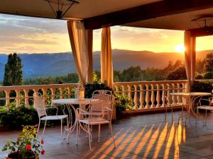 波加拉Hospedium Hotel Val de Pinares的阳台的天井配有桌椅,享有日落美景