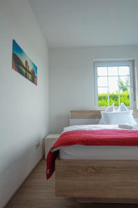 滨湖新锡德尔Pannonia Lake House的一间卧室配有一张带红色毯子的床和窗户。