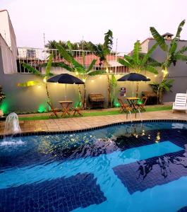 伊塔尼亚恩Hostel Praia Centro Itanhaém的一座房子内带桌子和遮阳伞的游泳池