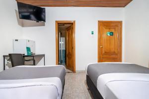 波哥大Hotel Quintas de Normandia的配有书桌和电视的客房内的两张床