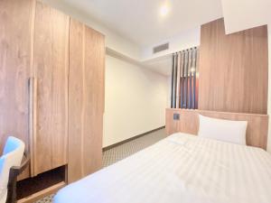 东京门屋酒店 的小房间设有一张床和木制橱柜