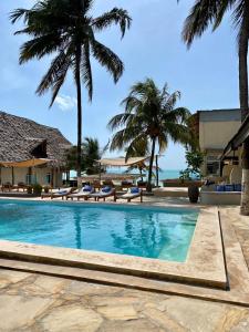 帕杰Paje Beach Apartments & Hotel的一座棕榈树和海洋游泳池
