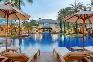 芭东海滩Holiday Inn Resort Phuket, an IHG Hotel的度假村的游泳池,配有椅子和遮阳伞