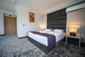 克尔贾利Hotel Caesar 2的一间卧室配有一张大床和黑色床头板