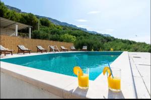 耶塞尼采Kuca za odmor Veronika的两杯橙汁坐在游泳池旁
