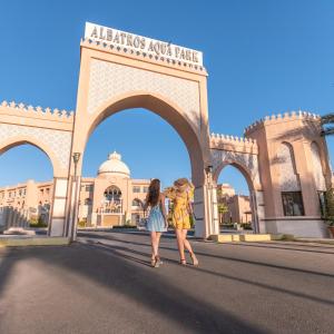 赫尔格达Pickalbatros Aqua Park Resort - Hurghada的两个女人在一座带拱门的建筑前行走