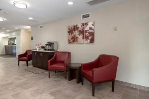 杰克逊维尔Red Roof Inn PLUS+ Jacksonville – Southpoint的一间设有红色椅子和柜台的等候室