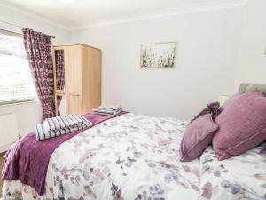 科尔温湾The Nook 285B的一间卧室配有一张带紫色枕头的床