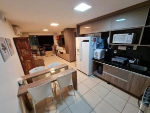 普赖尼亚Apartamento mobiliado Beach Place Porto das Dunas的厨房配有桌子和白色冰箱。