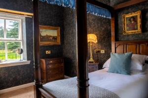 爱丁堡Melville Castle Hotel的一间卧室设有四柱床和窗户。