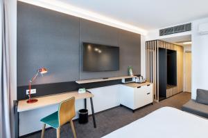 布拉格布拉格机场假日酒店的酒店的客房,设有书桌和墙上的电视