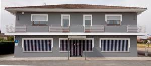 下卡尔瓦拉萨La Villa Hostal的灰色的房子,设有大门和阳台