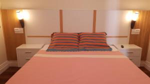 蓬塔德尔加达BRUMA HOSTEL的一间卧室配有一张带橙色和蓝色枕头的床