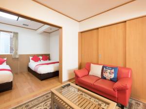 石卷市多摩经济型酒店的客厅配有红色的沙发和床。