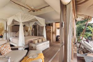 湄南海滩Khwan Beach Resort - Luxury Glamping and Pool Villas Samui - Adults Only - SHA Extra Plus的一间卧室配有天蓬床和沙发